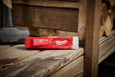 Red Milwaukee spirit level resting on wooden workbench in workshop
