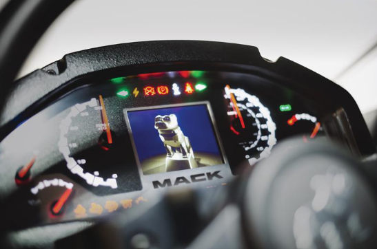 Mack Trucks logo on vehicle dashboard with illuminated instrument panel