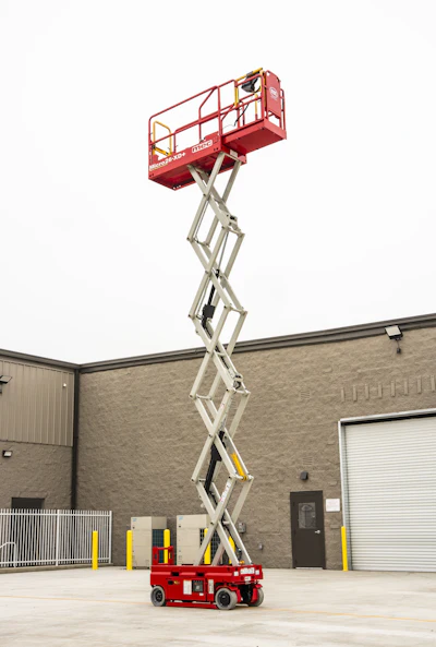 Red JLG scissor lift elevated at maximum height in front of industrial building