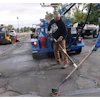 Construction workers repairing asphalt with blue equipment and machinery