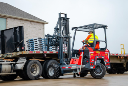 Red forklift loading blue pallets onto flatbed truck at industrial site