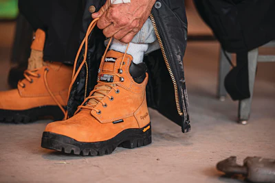 Rugged orange work boot with black sole being laced up