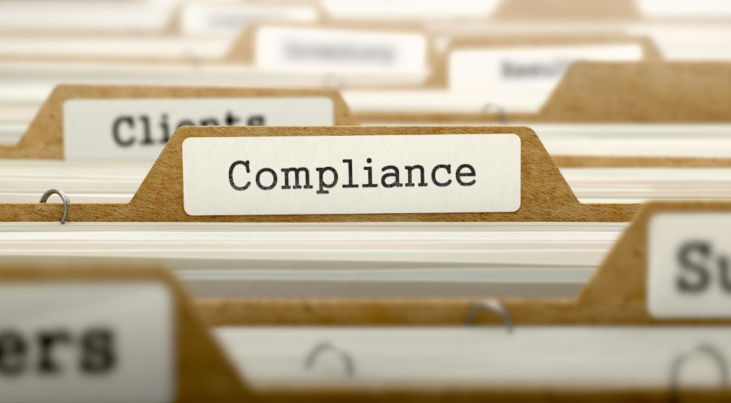Manilla file folder tab labeled 'Compliance' in a document filing system