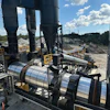 Industrial concrete batching plant with large storage silos, conveyor systems, and mixing equipment at a construction facility