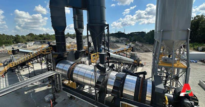 Industrial concrete batching plant with large storage silos, conveyor systems, and mixing equipment at a construction facility
