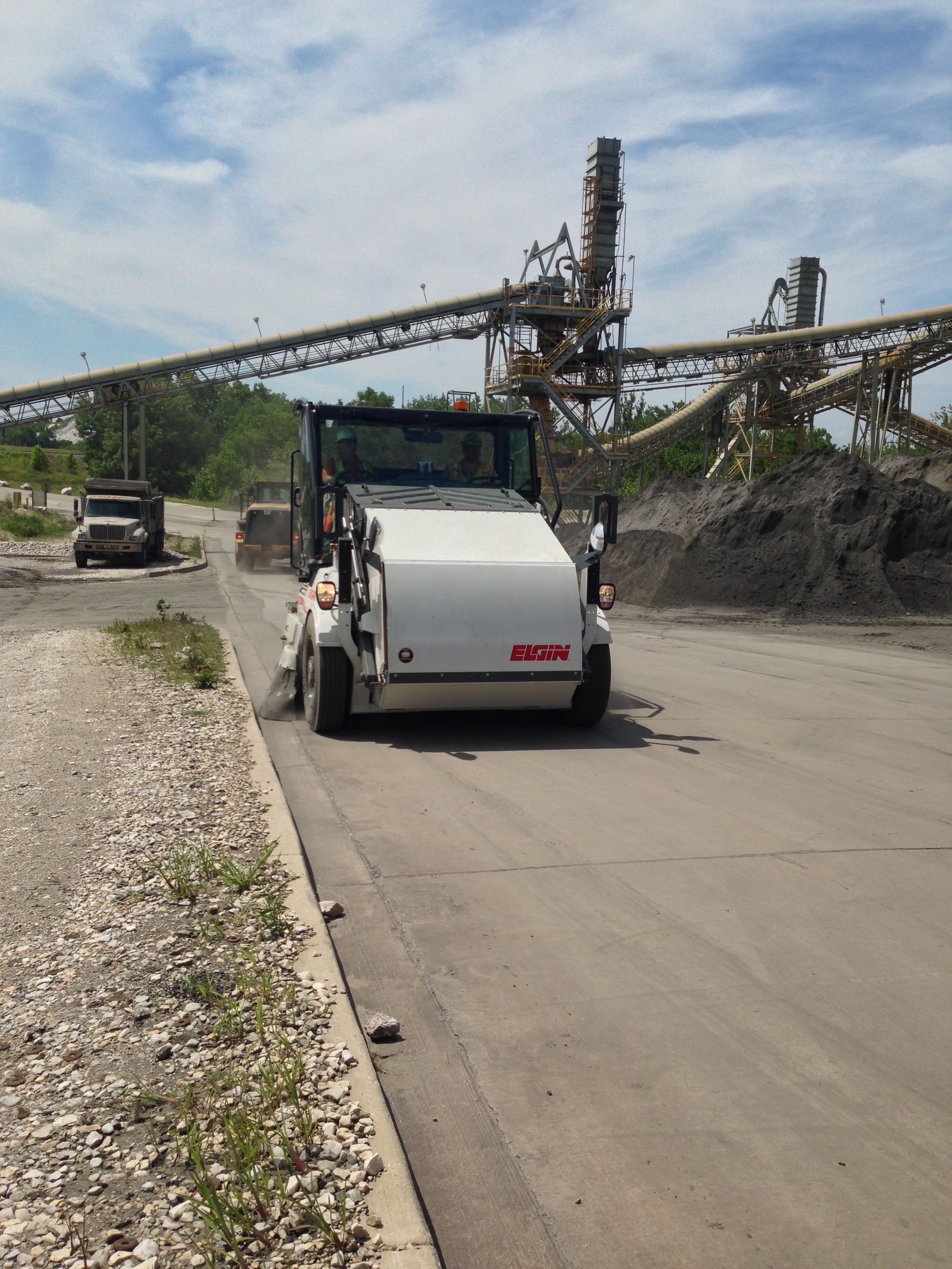 White Elgin concrete mixer truck at aggregate facility with conveyor belts and stockpiles