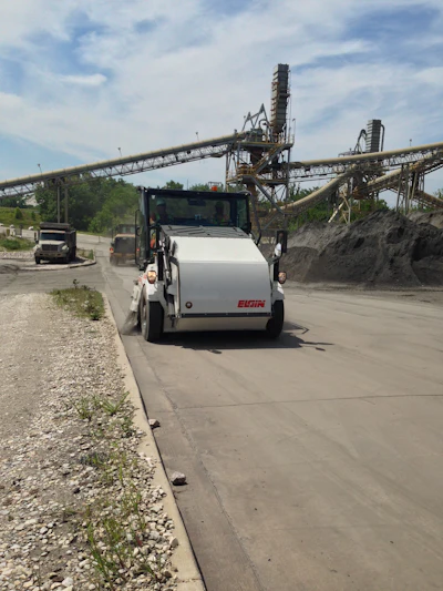 White Elgin concrete mixer truck at aggregate facility with conveyor belts and stockpiles
