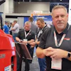 Professionals at trade show examining red VJR 26 equipment with branded signage in background