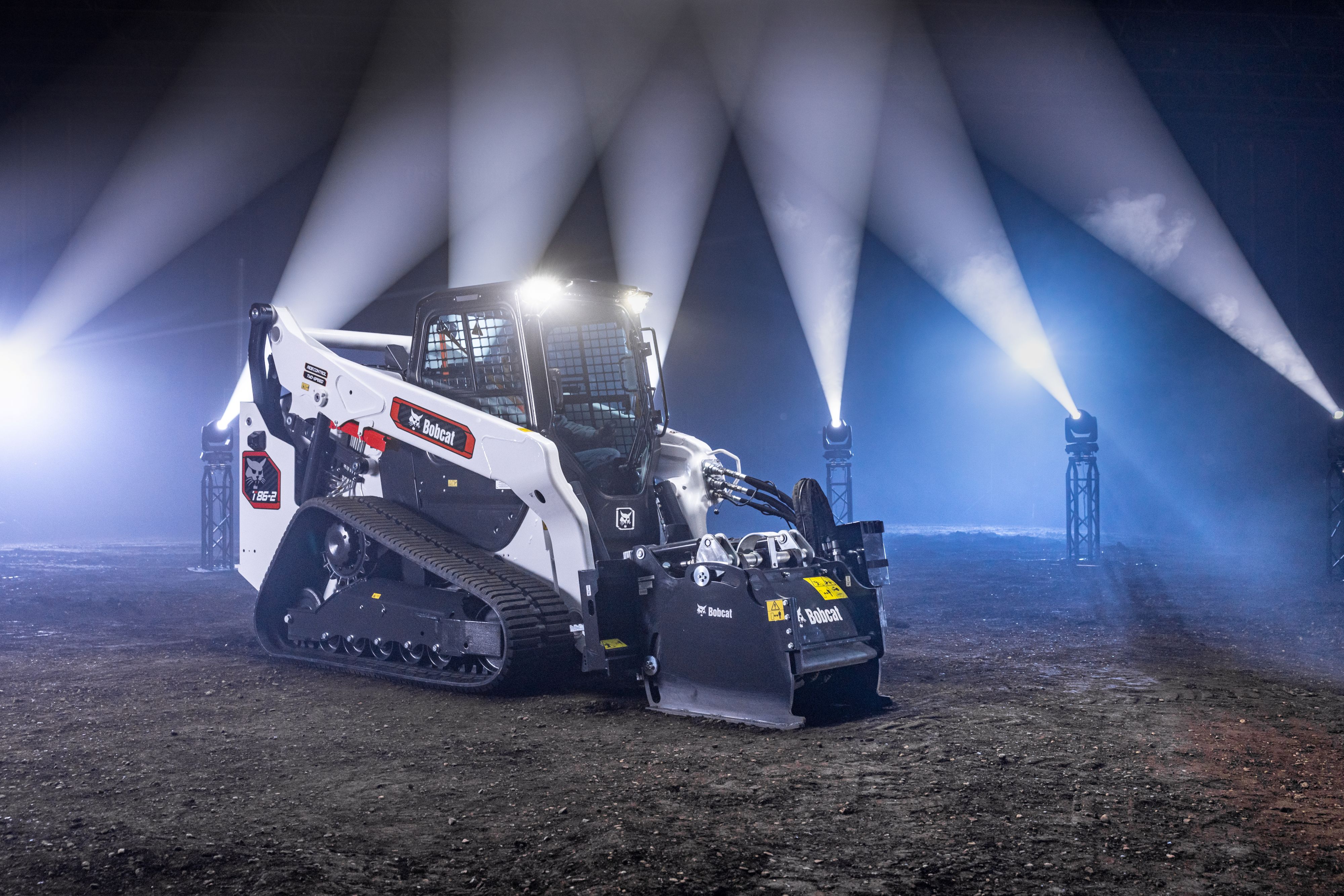 Bobcat skid-steer loader at night with dramatic industrial lighting beams