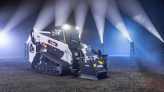 Bobcat skid-steer loader at night with dramatic industrial lighting beams