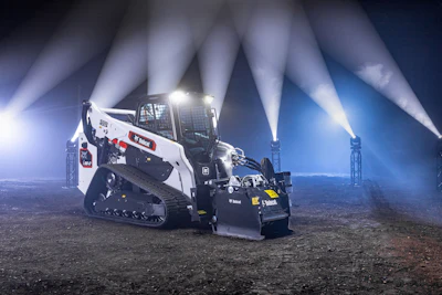 Bobcat skid-steer loader at night with dramatic industrial lighting beams