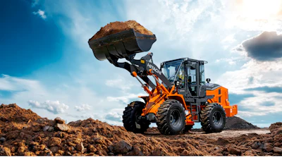 Orange XCMG wheel loader lifting soil at construction site with cloudy sky