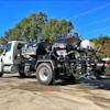 White and black Vac-Tron vacuum truck parked outdoors with blue sky and trees in background