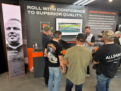 Trade show booth with visitors examining Smart Compact Pro technology display and product demonstrations