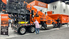 Bergkamp industrial wood chipping equipment displayed at trade show with orange machinery and mobile processing units