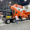 Bergkamp industrial wood chipping equipment displayed at trade show with orange machinery and mobile processing units