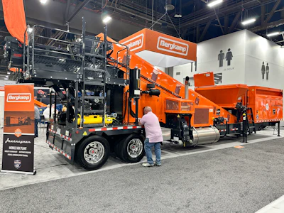 Bergkamp industrial wood chipping equipment display at trade show with orange machinery and visitor examining equipment