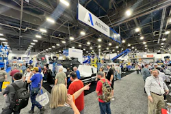 Busy trade show floor with crowds viewing industrial equipment and ASTEC branded displays under bright overhead lighting