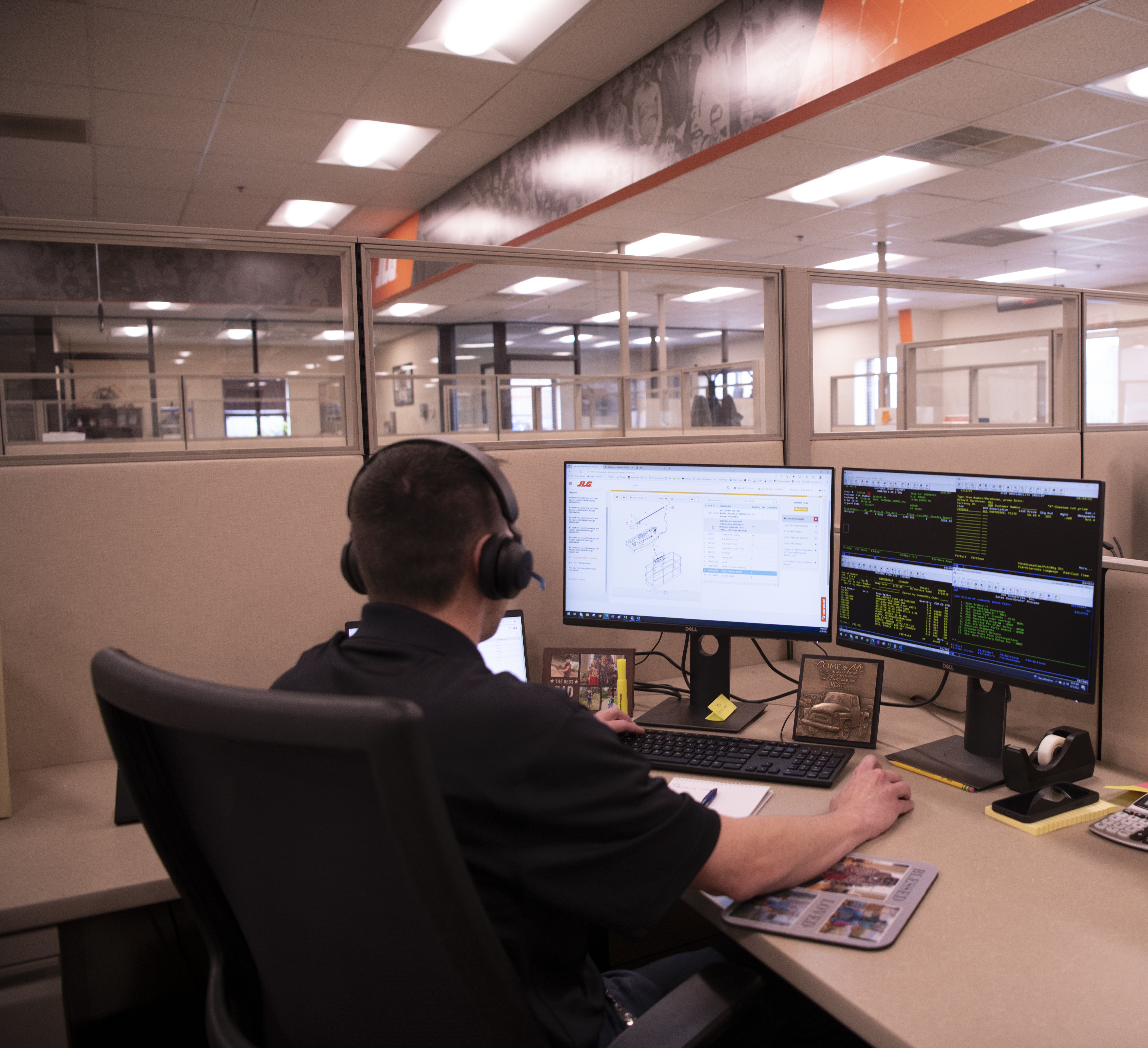 Professional working at dual-monitor workstation in modern office with headphones and technical displays