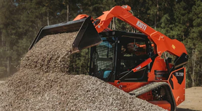 Red Bobcat telehandler loading gravel with forested background