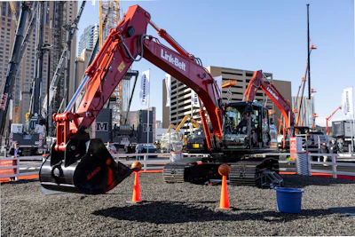 Red Link-Belt excavators displayed at outdoor construction equipment exhibition with city buildings in background