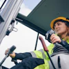 Female construction worker in safety gear operating heavy machinery on job site