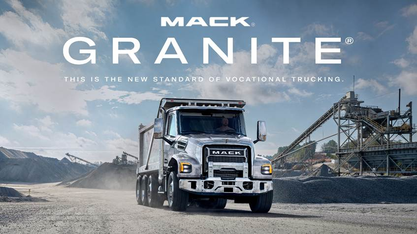 Mack Granite dump truck in industrial quarry setting with mountains and mining equipment in background
