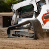 White and orange skid steer loader spreading dirt on construction site