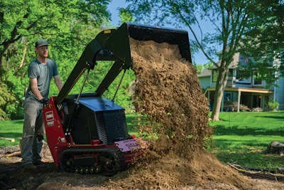 Worker operating red Toro wood chipper, dumping mulch in residential yard with trees