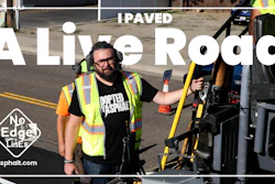 Worker in yellow safety vest holding measuring equipment on freshly paved asphalt road