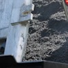 Truck bed filled with dark crushed stone aggregate material with red traffic light visible