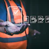 Worker in safety vest holding digital document management and quality assurance icons