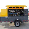 Yellow and gray mobile power generator trailer with engine compartment open in industrial yard