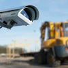Security camera mounted on pole overlooking construction site with yellow excavator and steel framework