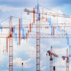 Construction cranes overlaid with financial candlestick charts against blue sky, symbolizing building growth and market investment
