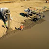 Construction workers pouring concrete at a job site with cement mixer truck and equipment