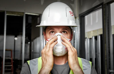 Construction worker wearing white hard hat and respiratory mask in safety gear