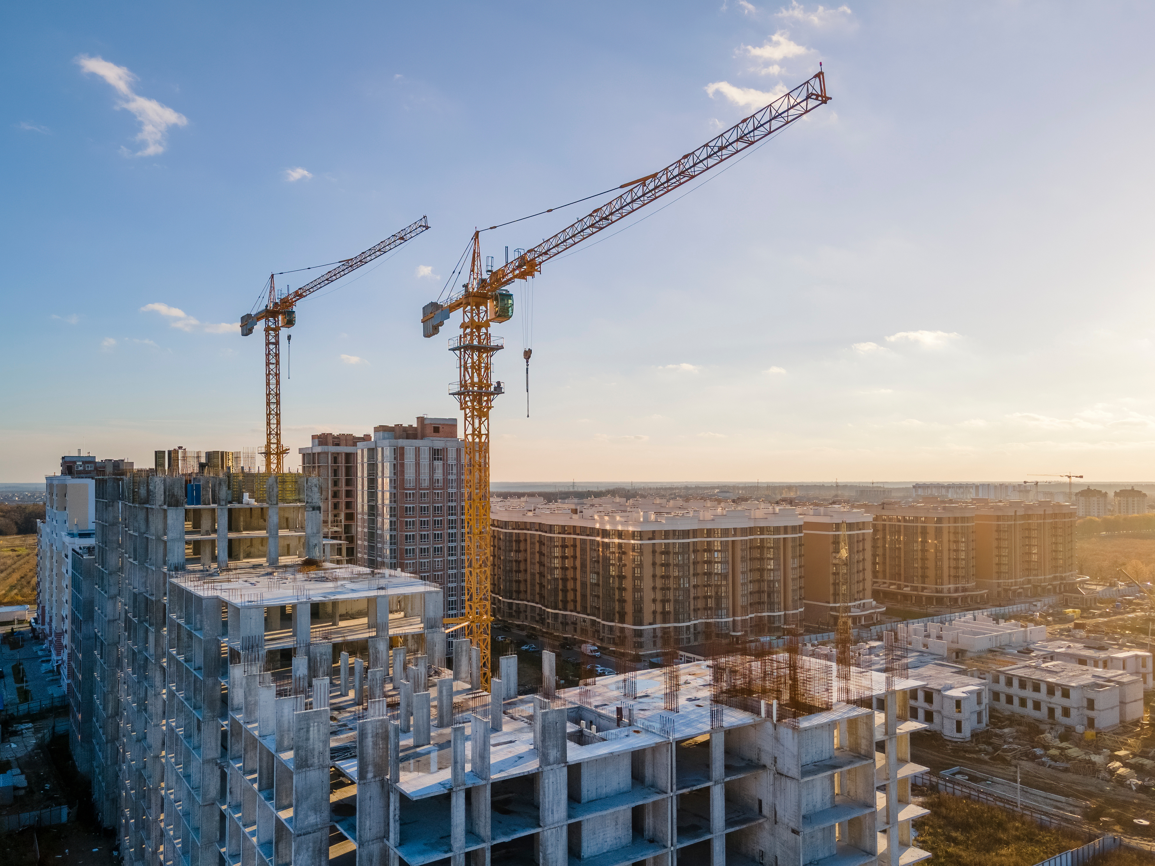 Construction site with tower cranes and multi-story residential buildings under development in urban landscape