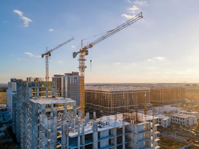Construction site with tower cranes and multi-story residential buildings under development in urban landscape