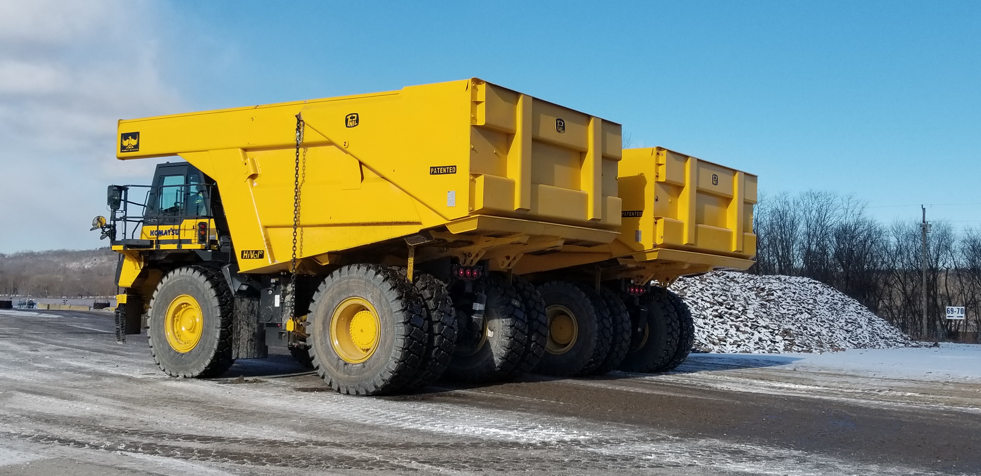Yellow Caterpillar articulated dump truck loaded with white aggregate material in an industrial yard