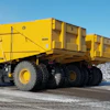 Yellow Caterpillar articulated dump truck loaded with white aggregate material in an industrial yard