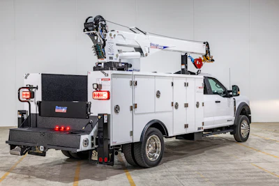 White utility truck with mounted crane and equipment compartment on concrete floor