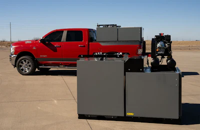 Red pickup truck with gray industrial equipment and black machinery displayed in outdoor parking lot
