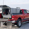 Red pickup truck with open emergency equipment compartment and metal storage boxes mounted on rear