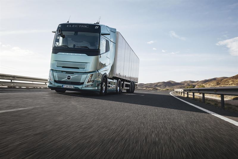 Volvo electric truck driving on highway with white trailer in daylight