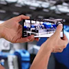 Person holding smartphone recording video inside industrial facility with blue equipment