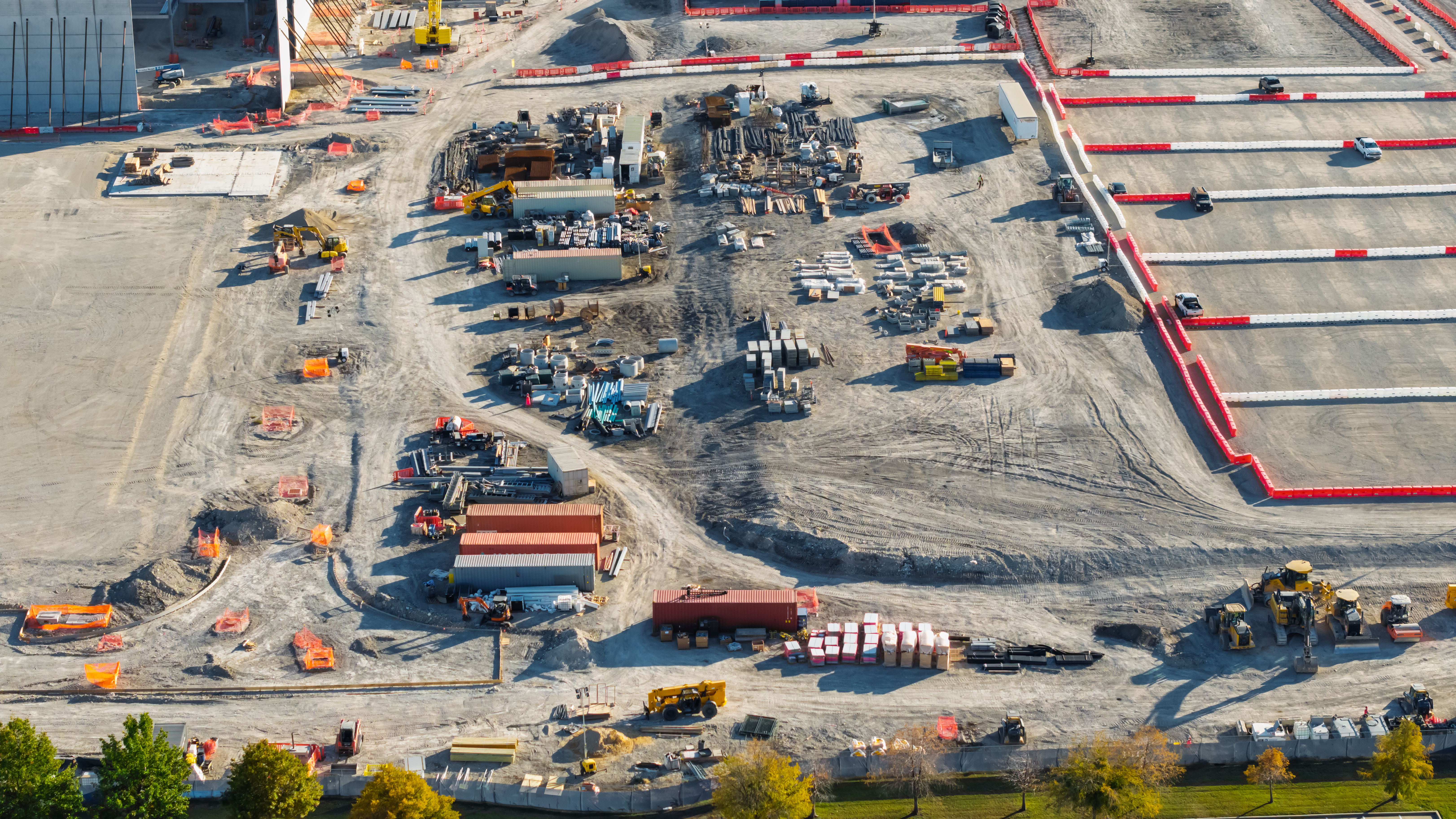 Aerial view of active construction site with heavy machinery, materials, and ongoing excavation work
