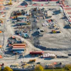 Aerial view of active construction site with heavy machinery, materials, and ongoing excavation work