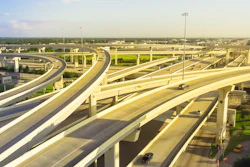 Aerial view of multilevel highway interchange with elevated concrete roadways and light traffic under clear sky