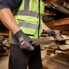 Construction worker wearing neon safety vest and work gloves handling wood materials in warehouse